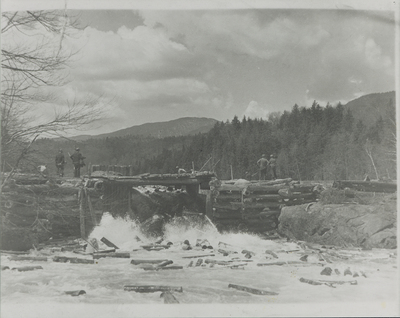 Loggers move logs through a dam gate on Henderson Lake, NY in 1935.