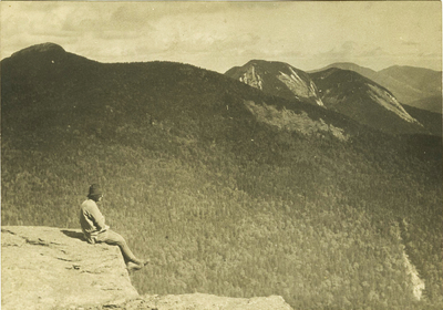 Solitary figure takes in the majestic beauty of the Adirondack mountains, c. 1915.