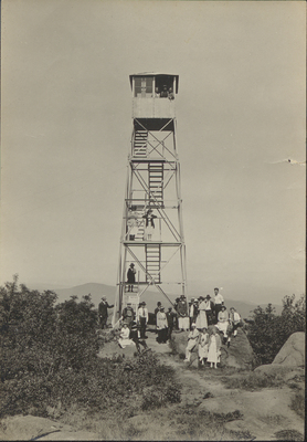 Hikers posing in front of the fire tower at the summit of Black Mountain, NY, circa 1920.
