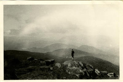 Figure taking in the view of Adirondack peaks from the summit of an unknown mountain, c. 1915.