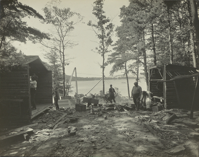 Six figures tearing down squatters' cabins on Big Burnt Island in Lake George, NY, 1917.