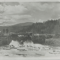 Loggers move logs through a dam gate on Henderson Lake, NY in 1935.