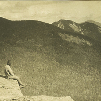 Solitary figure takes in the majestic beauty of the Adirondack mountains, c. 1915.