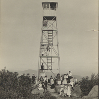 Hikers posing in front of the fire tower at the summit of Black Mountain, NY, circa 1920.