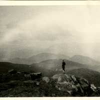 Figure taking in the view of Adirondack peaks from the summit of an unknown mountain, c. 1915.