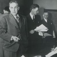 Photograph of Assemblyman John Ostrander, Paul Schaefer, and Sanford D. Stockman standing in suits in front of a table during the two day Ostrander Amendment public hearings at the American Museum of Natural History in New York City on January 20-21, 1950.