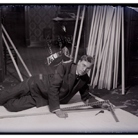 Dr. Irving Langmuir in repose measuring cloth for skate sails in 1910. The glass negative has a second exposure showing part of lamp shade made from a wrapper for N.B.C. Soda Crackers, c. 1910.