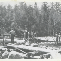 River drivers standing on docks on Henderson Lake, NY surrounded by logs, May 1931. They are waiting for the wind to change from the south to the west to blow the logs across the lake to a dam which will send them down the Henderson River to the lumber mills on the Hudson River. Bill Gluesing and Paul Schaefer took this on a trip to photograph Indian Pass from Henderson Lake.