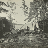 Six figures tearing down squatters' cabins on Big Burnt Island in Lake George, NY, 1917.