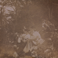 Nine men, women, and children in Edwardian dress picnicking in the Adirondacks, c. 1900.